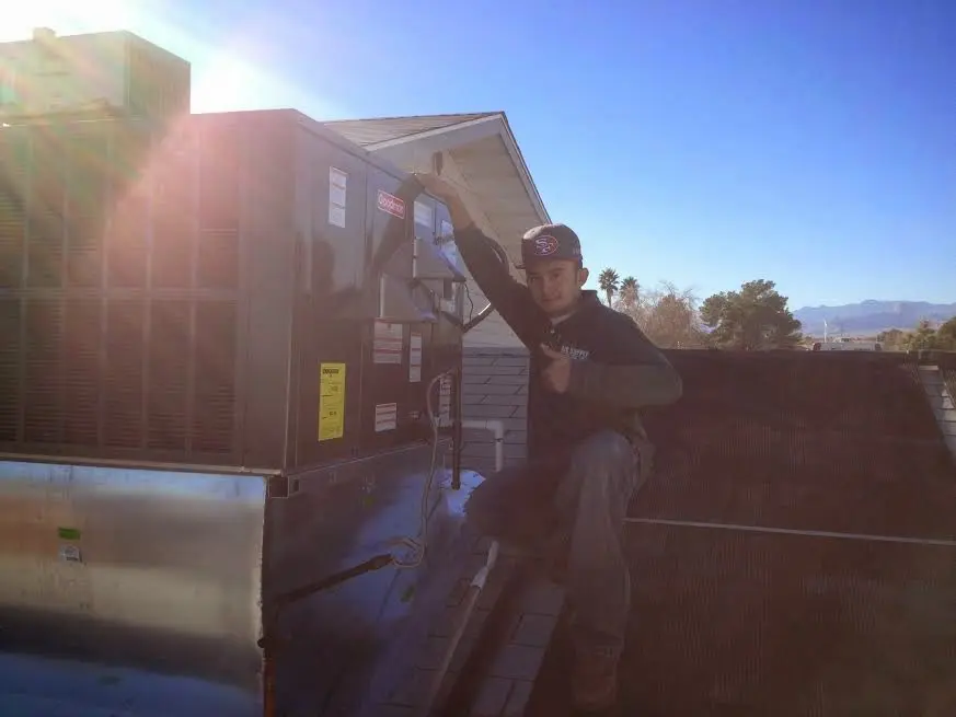 HVAC technician performing AC Tune-Up on a rooftop unit in Falls